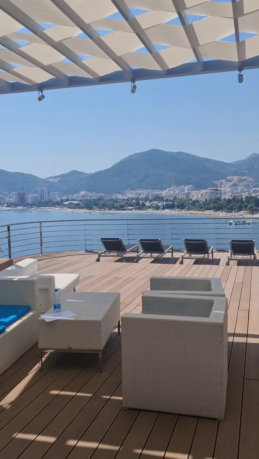 The studio terrace: white armchairs under a pergola, looking across the bay to Budva and the mountains